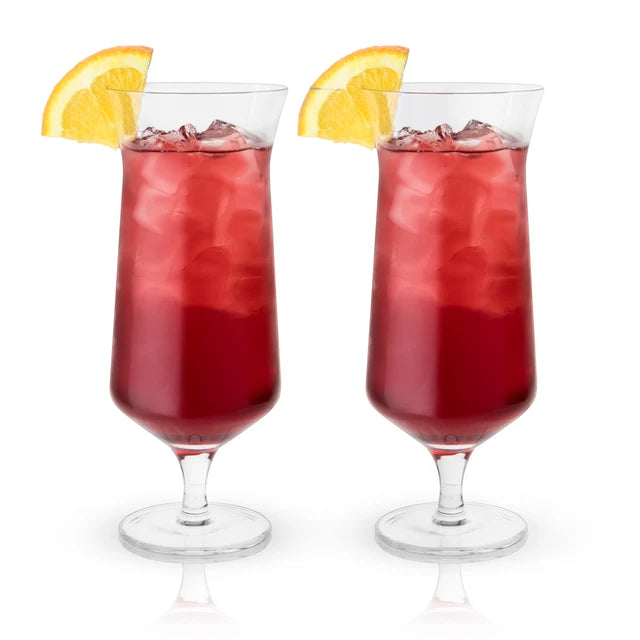 Dos copas de cristal estilo hurricane sin plomo con cóctel rojo, hielo y rodaja de limón